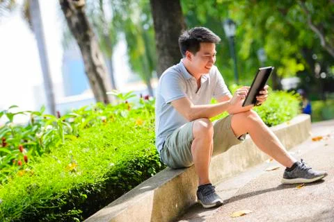 Young asian man using tablet in summer park Stock Photos