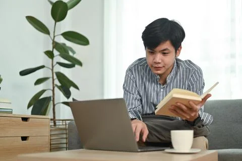 Young asian man using using laptop computer, working online or checking his 写真素材