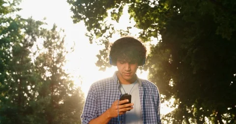 Young asian man walking down the street, using smartphone listening to music in Stock Footage 93444805