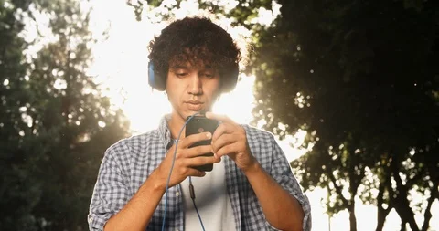 Young asian man walking down the street, using smartphone listening to music in Stock-Footage 93445598