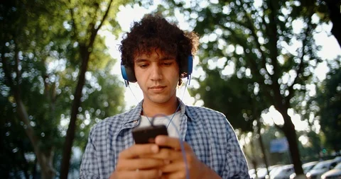Young asian man walking down the street, using smartphone listening to music in Vidéo 93449100