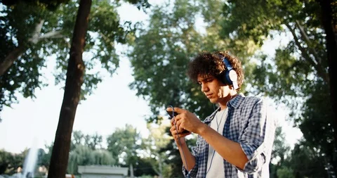 Young asian man walking down the street, using smartphone listening to music in Stock Footage 93452989
