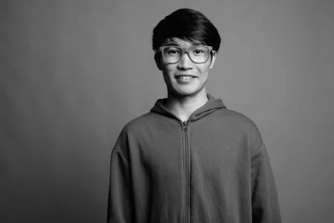 Young Asian man wearing jacket with eyeglasses against gray background Stock Photos