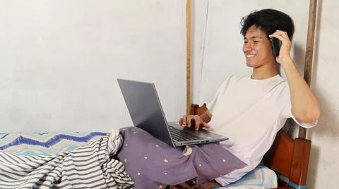 Young asian men playing, using, watching, video calling, discussing using a.. 写真素材