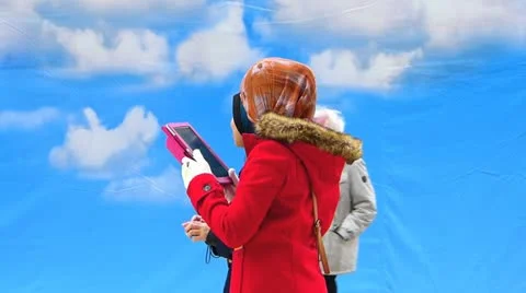 Young Asian Muslim girls in headscarf using tablet iPad European city Stock Footage