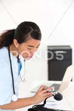 Young Asian Nurse At Desk Checking Pressure Pump