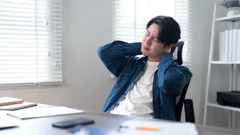 Young Asian office worker experiencing neck pain and discomfort while worki.. Stock Photos