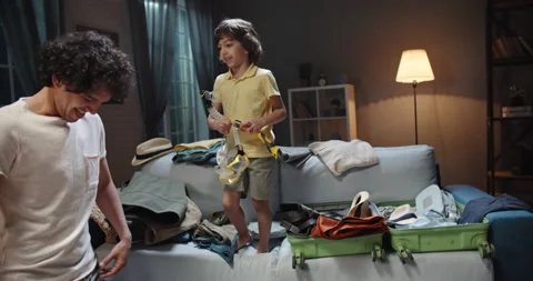 Young asian parents are closing a tightly packed suitcase while their funny kiud Stock Footage