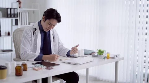 Young Asian physician examining medication and writing prescription notes a.. Stock Footage 341455865