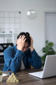Young Asian professional experiencing work stress sitting at home office de.. Stock Photos