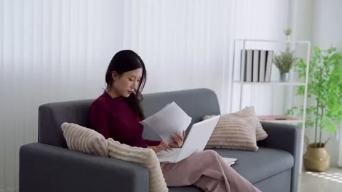 Young Asian professional reviewing documents and using laptop while working.. Stock Footage 337367754