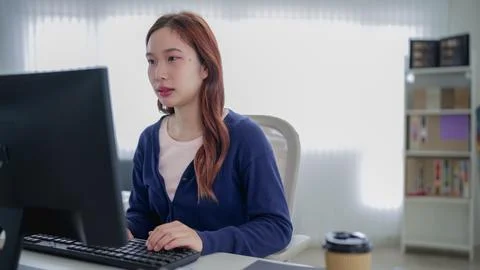 Young Asian professional working on computer in bright modern home office w.. Stock Photos