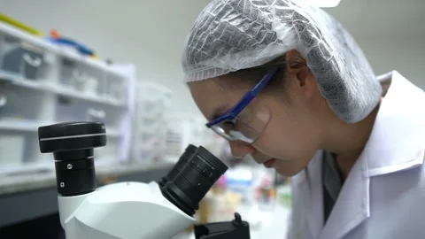 Young asian scientist looking through a microscope in a laboratory Stock Footage 196963737