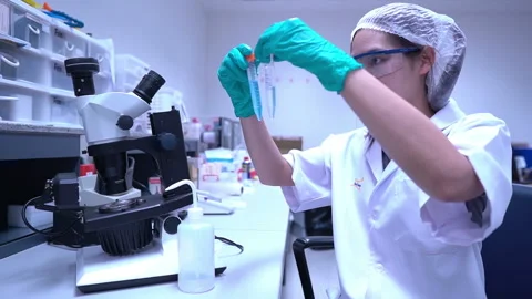 Young asian scientist looking through a microscope in a laboratory Stock Footage 196964449
