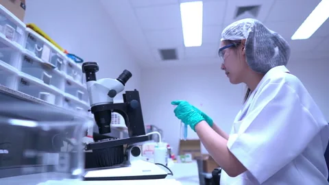 Young asian scientist looking through a microscope in a laboratory Stock Footage 196964648