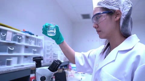 Young asian scientist looking through a microscope in a laboratory Stock Footage 196964937