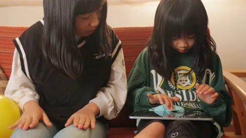 Young asian sisters having fun with a digital tablet at home. Stock Footage 228285435
