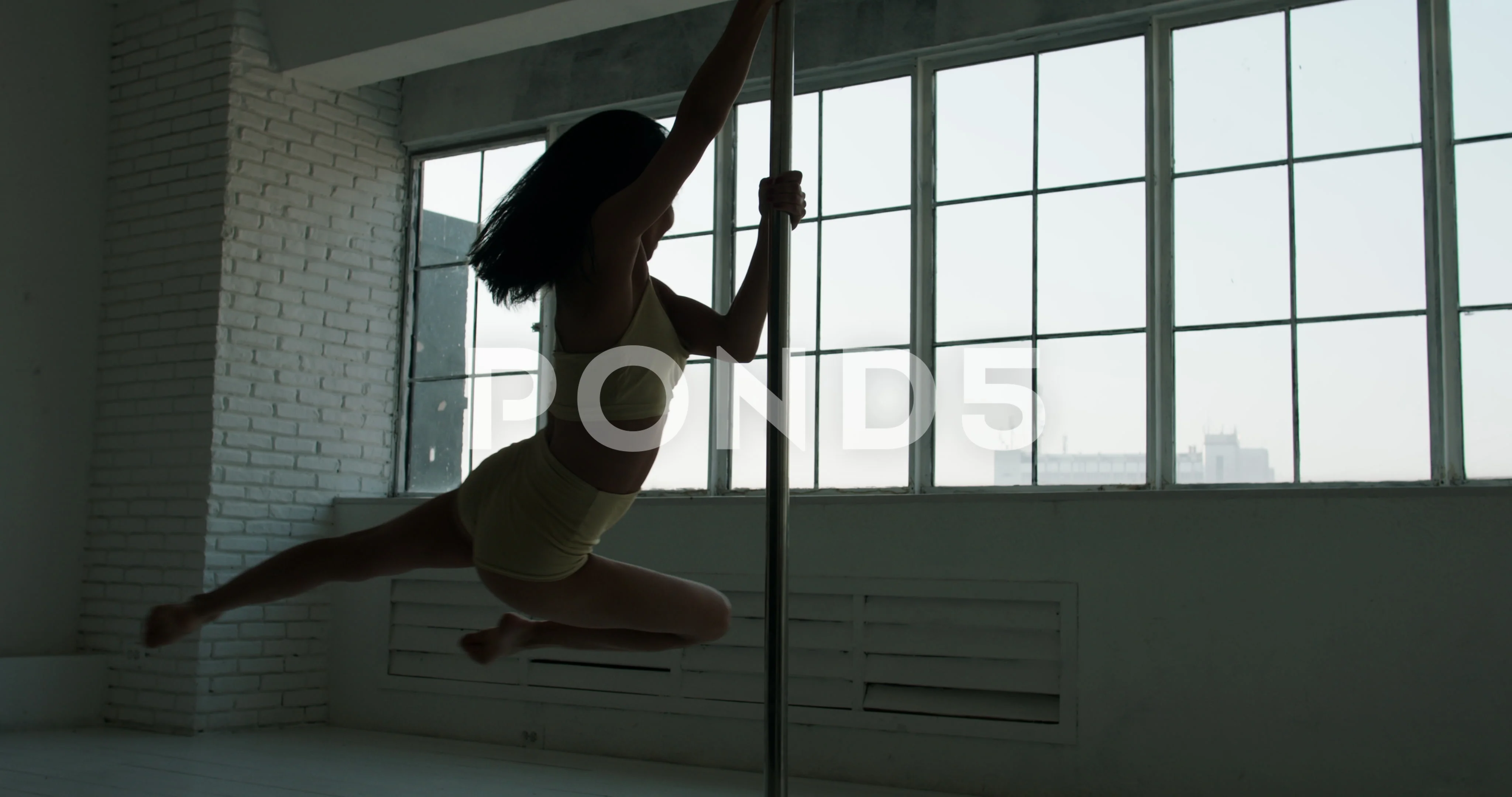 Young Asian strippers girl Silhouette dances on a pylon bright studio big