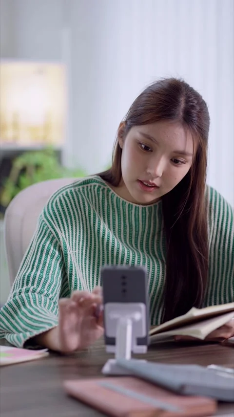 Young Asian student checking smartphone while studying with textbooks and n.. Stock Footage 342533481