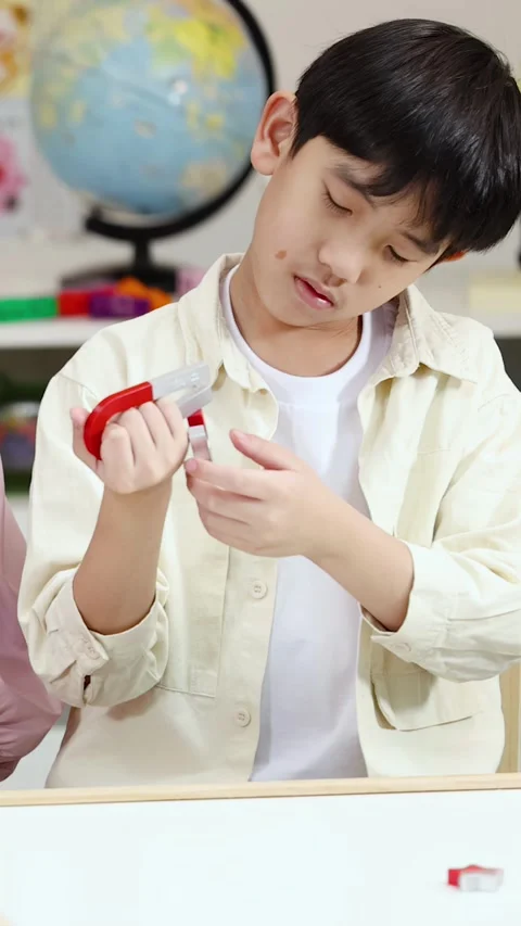 Young Asian Student Exploring Magnetic Force with Horseshoe Magnets in Classroom Stock Footage 325298085