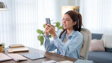 Young Asian student smiling while using smartphone for mobile education at .. Stock Photos