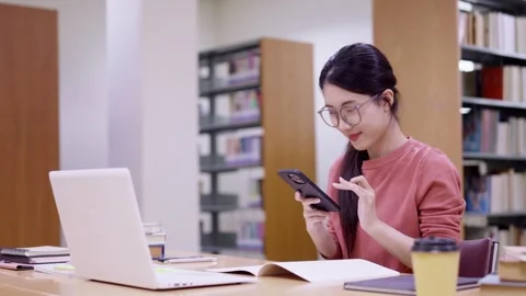 Young Asian student using smartphone mobile phone with laptop computer note.. Stock Footage 335003367