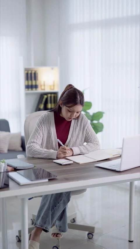 Young Asian student writing notes in notebook while studying with laptop at.. Stock Footage 341682744