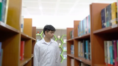 Young asian is walking between book shelf,choose books in the library,Concept Stock Footage 122586179