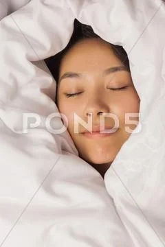 Young asian woman all wrapped up in her duvet Stock Photos