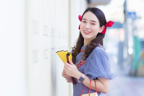 A young Asian woman in a blue-gray cheongsam holds a cloth bag. Stock Photos