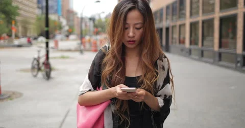Young Asian woman in city texting on cell phone walking Stock Footage