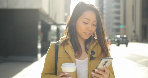 Young Asian woman in city walking texting cell phone slow motion Stock Footage