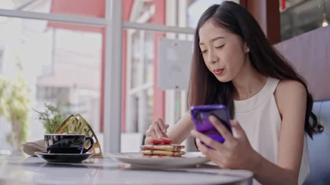 A young Asian woman happily eats pancakes topped with strawberries and chocolate Stock Footage 252108243