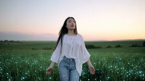 Young asian woman happily walking in slow motion through a field touching with Stock Footage 166323339