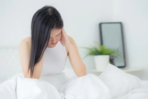 Young asian woman sitting on bed pain headache in the bedroom at home, unha.. Stock Photos