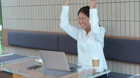 Young Asian woman using a computer with a happy expression for success at cafe Stock Footage 244104738