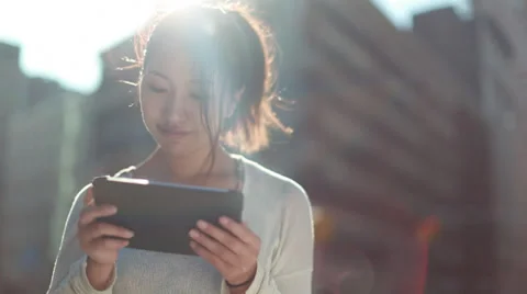 Young Asian woman using iPad tablet on a city street Stock Footage