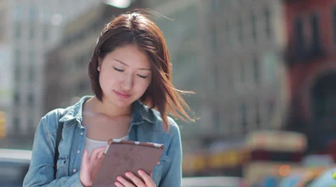 Young Asian woman using iPad tablet pc computer in a city Stock Footage
