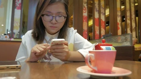 Young Asian Woman using smartphone at restaurant Stock Footage