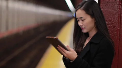Young Asian woman using tablet pc reading subway platform Stock Footage