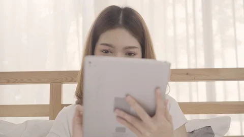 Young Asian woman using tablet while lying on bed after wake up in the morning. Stock Footage 101381841