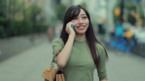 Young Asian Woman walking street talking on cellphone Stock Footage