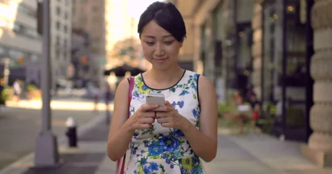 Young Asian woman walking texting cell phone Stock Footage