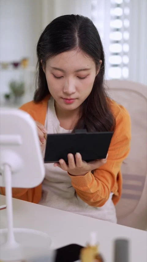 Young Asian women applying makeup with brush using mirror doing beauty rout.. Stock Footage 334327853