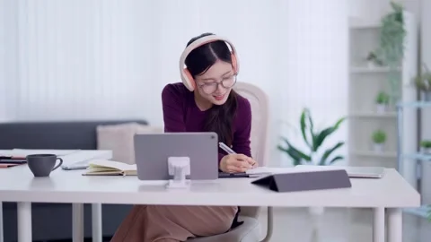 Young Asian women student using tablet computer wearing headphones studying.. Stock Footage 334358510