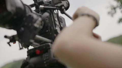 Young assistant supports camera on tripod for steady shot Stock Footage 306553236