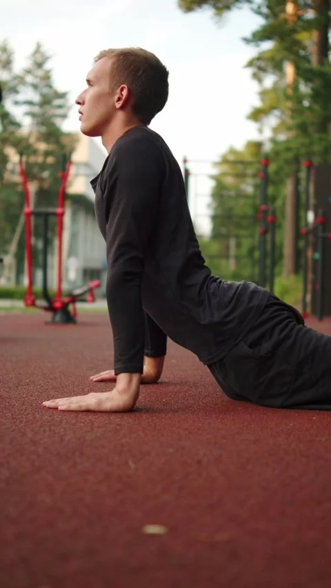 Young athlete in black athletic clothes performing a cobra pose stretch on .. Stock Footage 341728634