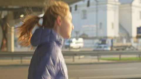 Young athlete in blue jacket jogging on sidewalk in urban landscape Video stock 133268833