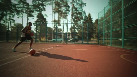 A Young Athlete Diligently Practicing Basketball Skills on an Outdoor Court for Stock Footage 301463389