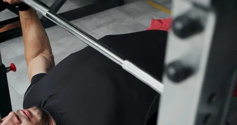 Young athlete is doing bench press in gym.Man lies on bench and does exercise Stock Footage 116513089